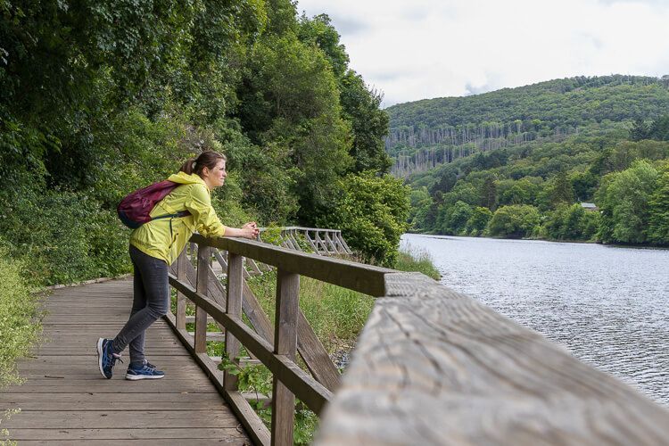 Ich genieße die Aussicht auf die Landschaft. Wanderung um das Rur-Staubecken. Eine Frau steht am Ufer und blickt aufs Wasser.