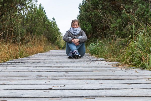 Eine Frau sitzt auf dem Holz-Wanderweg zum Hochmoor bei Kaltenbronn.