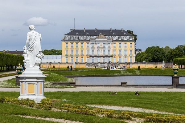 Schloss Augustusburg in Brühl mit einer weißen Skulptur im Vordergrund.