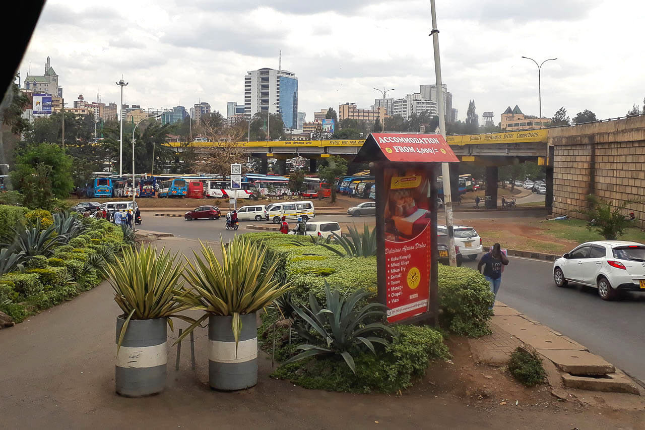 Blick vom Frühstückstisch auf einen Kreisverkehr in Nairobi Straßen von Nairobi mit viel Verkehr und Matatus im Hintergrund.