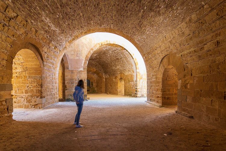 In der Festung von Syrakus auf Sizilien. Eine Frau steht in mächtigen gewölbten Gängen einer Festung. Licht scheint herein