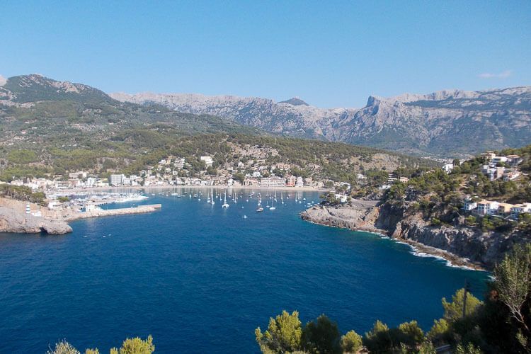Blick auf Port de Sóller, Mallorca. Blick von einer Anhöhe auf den die Bucht von Port de Sóller, Mallorca. Das Wetter ist schön, blauer Himmel, im Hafen liegen Segelboote, im Hintergrund ist das Tramuntana-Gebirge