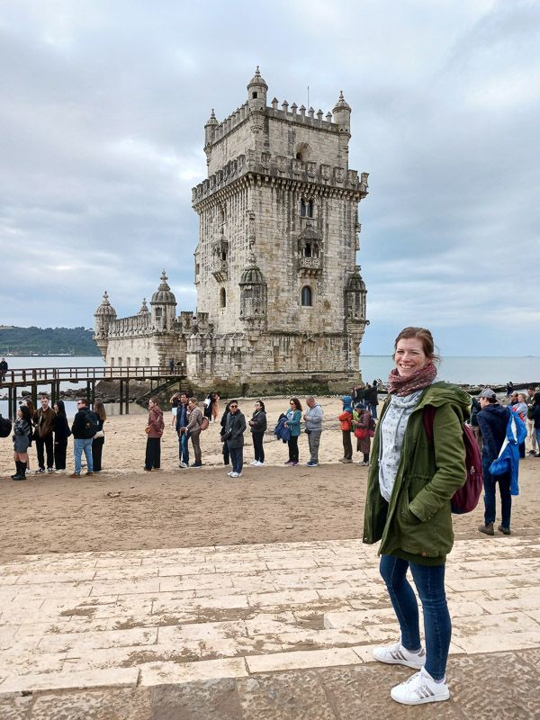 Sightseeing in Belém Eine Frau posiert lachend vor dem Torre de Belém in Lissabon.