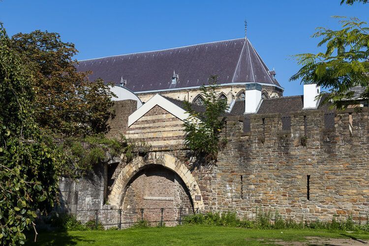 Alte Stadtmauer von Maastricht Historische Stadtmauer in Maastricht mit einer Kirche, die über die Mauern hinausragt.