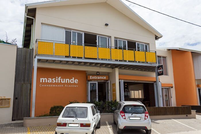 Hauptgebäude des Masifunde-Bildungszentrums in Walmer Township. Außenfassade des Bildungszentrums Masifunde in Walmer Township. Vor dem Gebäude stehen zwei Autos.