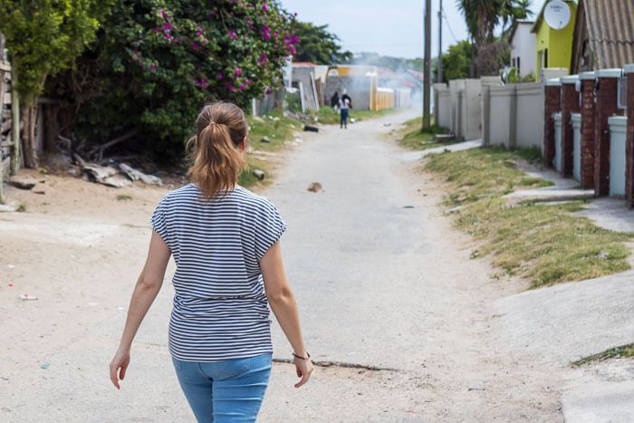 Unterwegs in Walmer Township. Eine weiße Frau läuft zu Fuß durch Walmer Township in Südafrika.