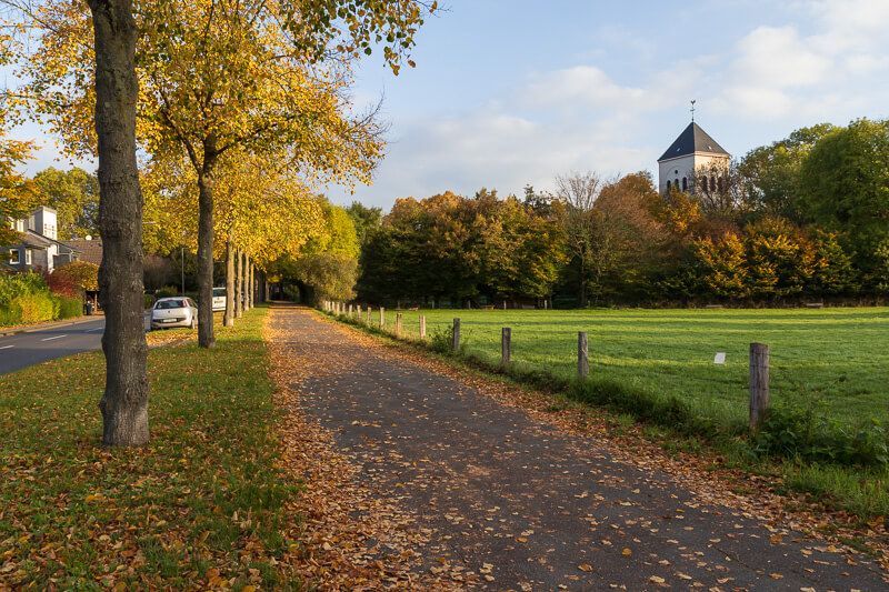 Merheim als Oase der Ruhe Herbstliche Straße in Merheim mit Wiese und Kirche im Hintergrund.