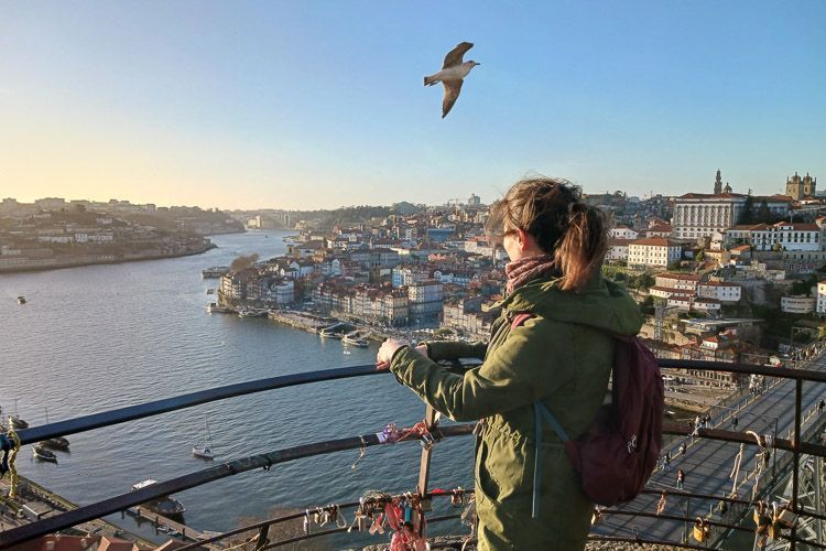 Sonnenuntergang in Porto Eine Frau sieht sich den Sonnenuntergang von Porto an, eine Möwe fliegt durchs Bild.