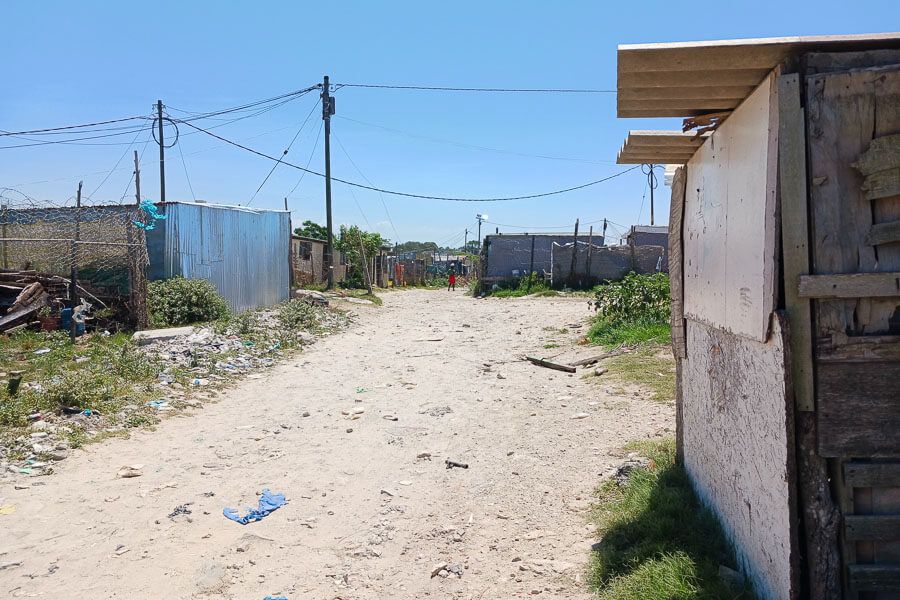 Blick eine Straße herunter mit Verschlägen, Stromleitungen und Müll Blick eine Straße herunter mit Verschlägen, Stromleitungen und Müll