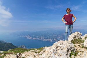 Frau steht auf dem Gipfel des Monte Baldo, weit unten ist der Gardasee.