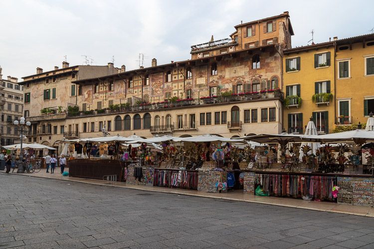 Die Piazza delle Erbe mit vielen Marktständen und kunstvoll bemalten Fassaden. Die Piazza delle Erbe in der Altstadt von Verona mit vielen Marktständen und kunstvoll bemalten Fassaden.