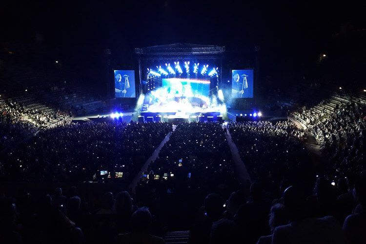 Konzert der Scorpions Scorpions-Konzert in der Arena di Verona. Es ist dunkel, die Scheinwerfer erleuchten die Bühne. Zu sehen ist außerdem der voll besetzte Zuschauerraum.