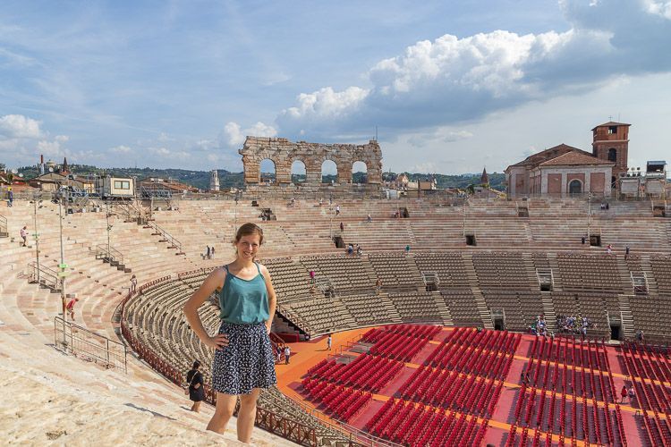Sehenswürdigkeit Verona: Amphitheater Eine Frau steht im Zuschauerraum der Arena di Verona. Weite Perspektive auf die Arena vom obersten Rang.