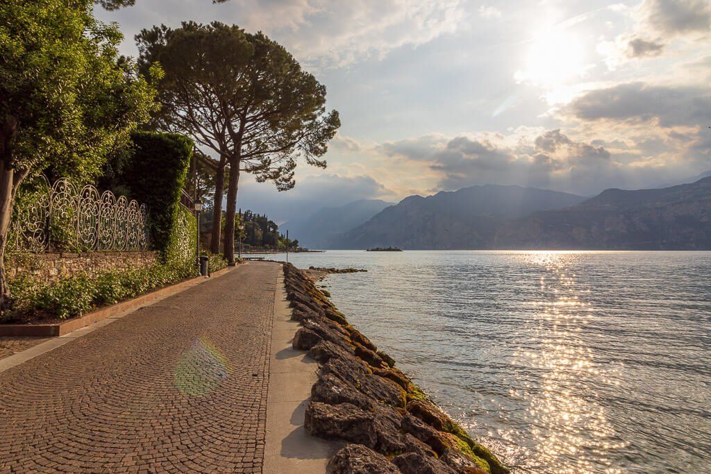 Spaziergang am Gardasee mit herrlicher Ruhe Alleine am Gardasee hinter Malcesine entlangschlendern. Die Sonne kommt hinter den Wolken hervor und glitzert auf dem Wasser.