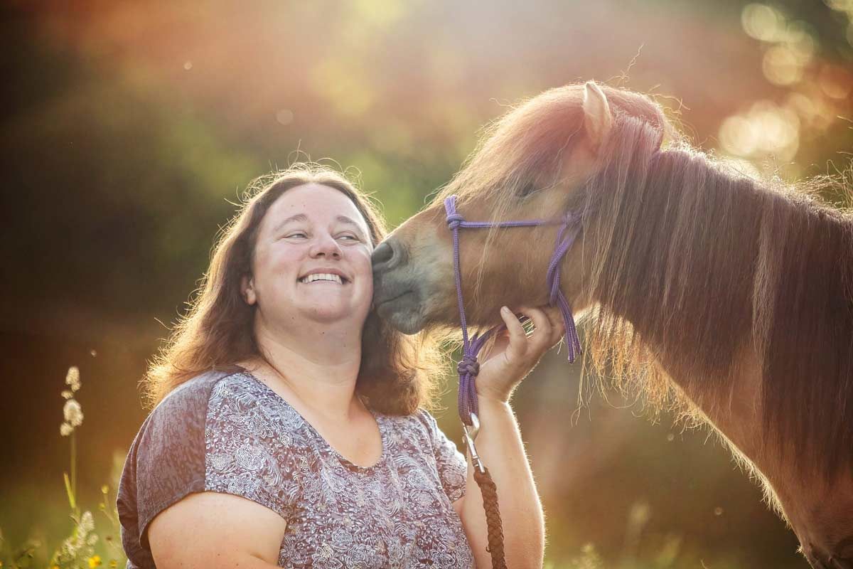 LL Photography Mensch und Tier: Eine Frau kuschelt im Morgenlicht mit einem Shetland-Pony