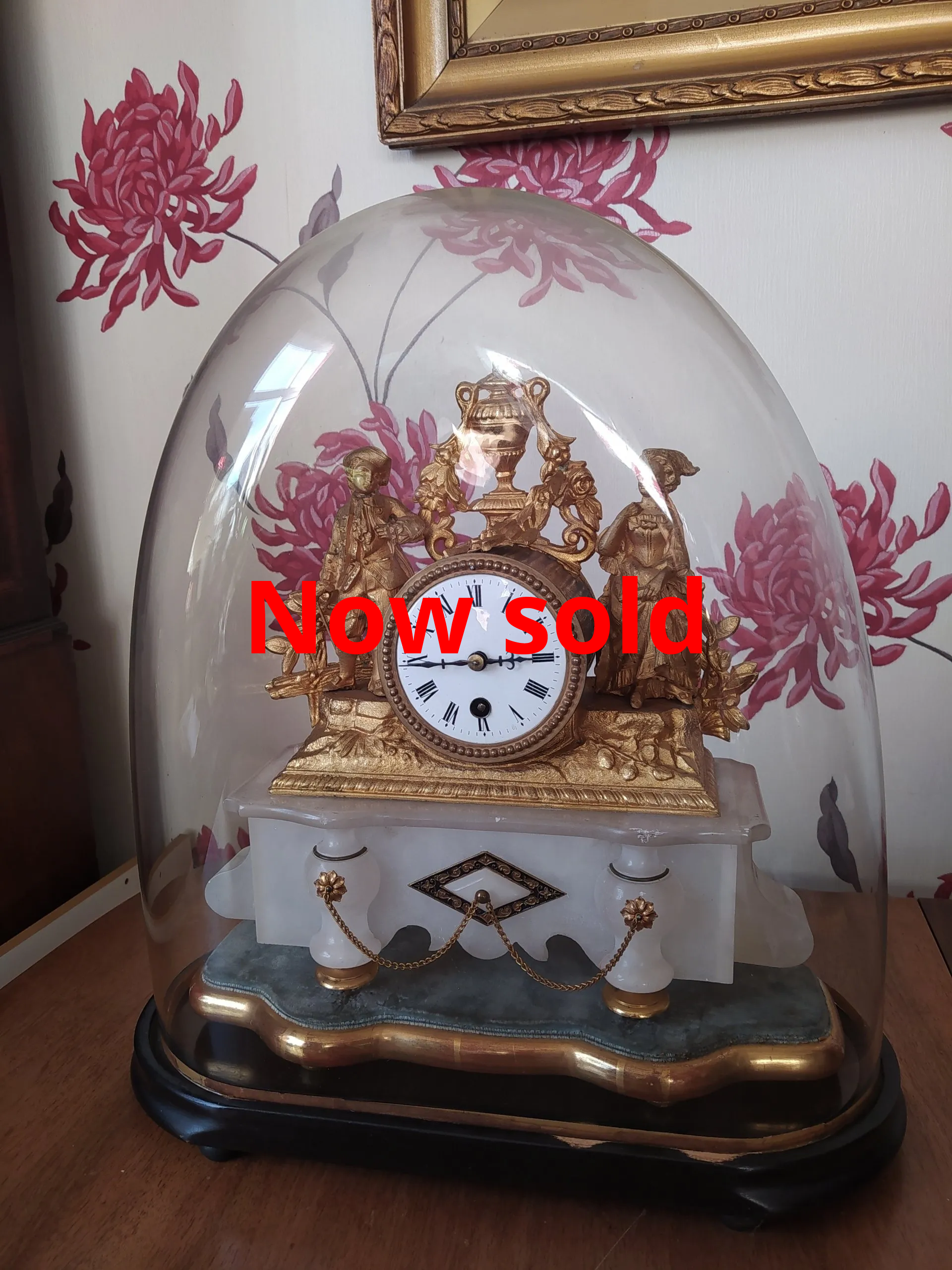 antique french alabaster and gilt metal clock under a glass dome.