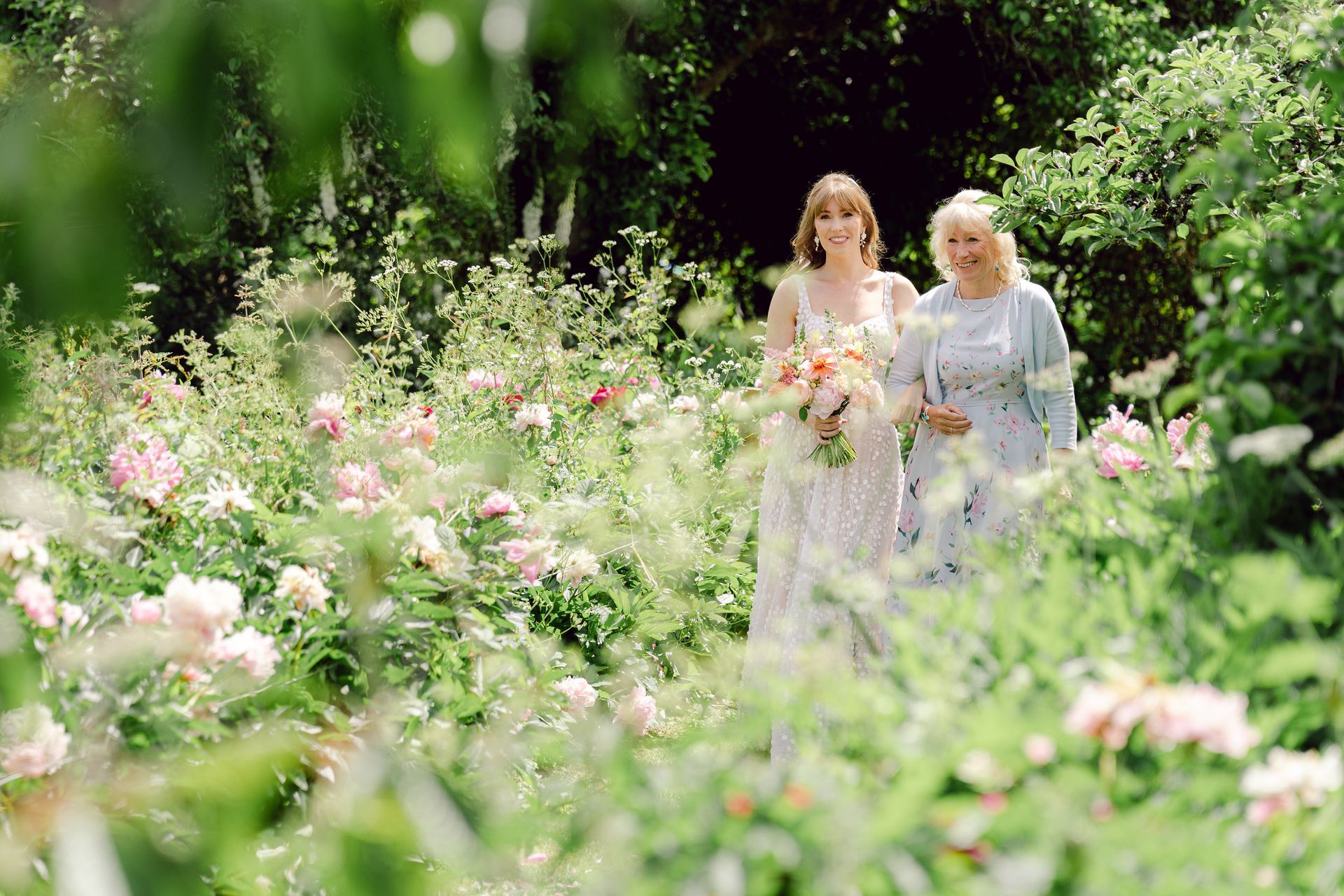 Bride and mum walking down the wedding aisle surrounded by peonies in bloom at Kingsettle Stud - co-ordinated by Tasha Mae Wedding Co-ordinator.