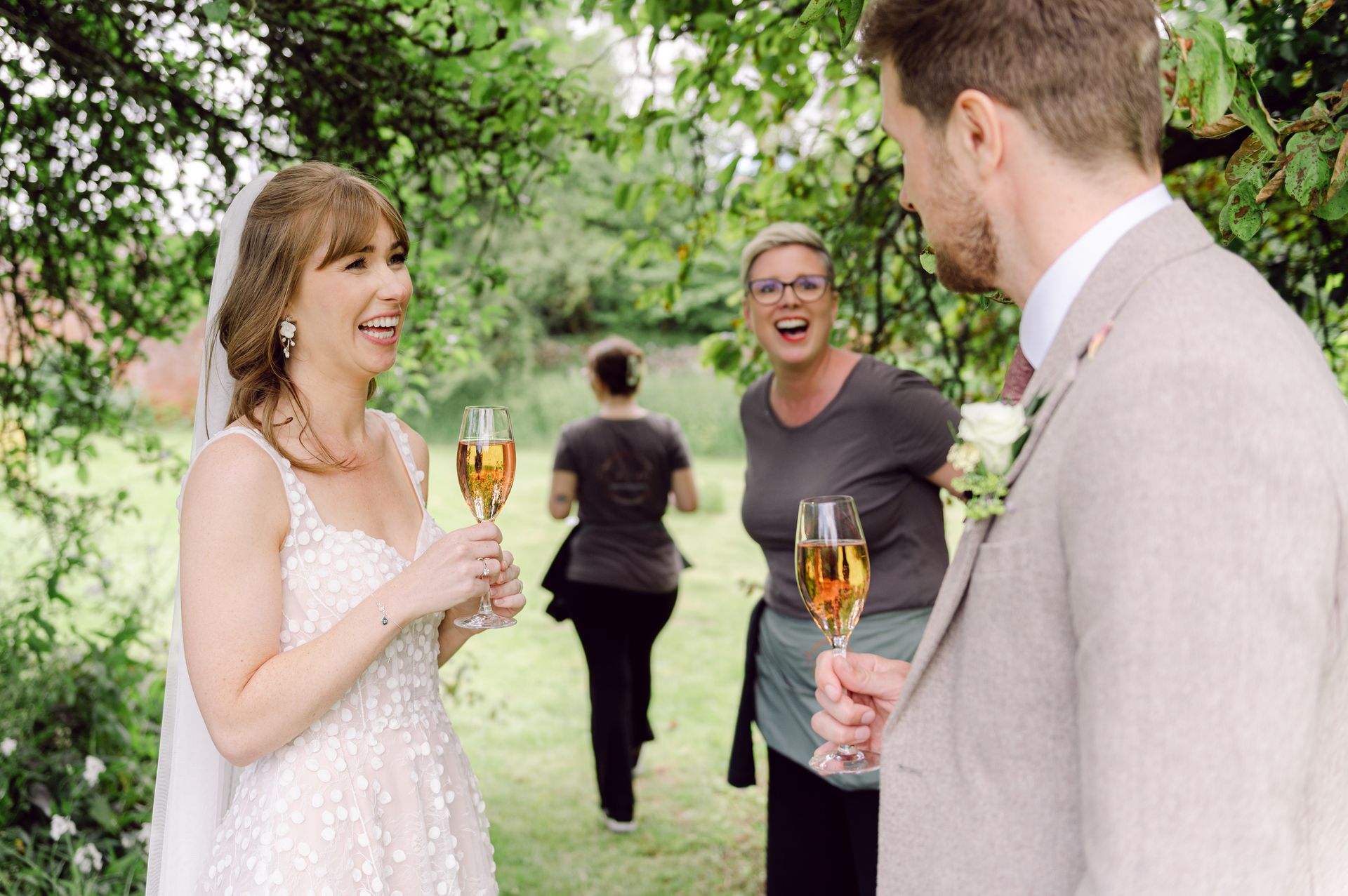Bride and groom with a glass of champagne and Tasha Mae Wedding Co-ordinator at Kingsettle Stud.