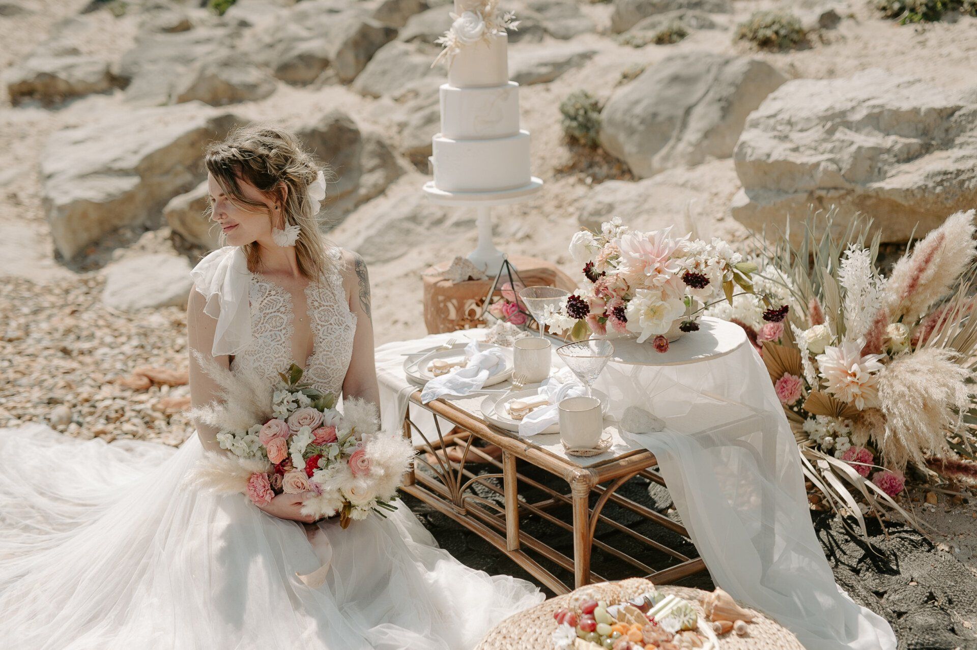 Bride sat at picnic table with flowers on Highcliffe Beach in Dorset