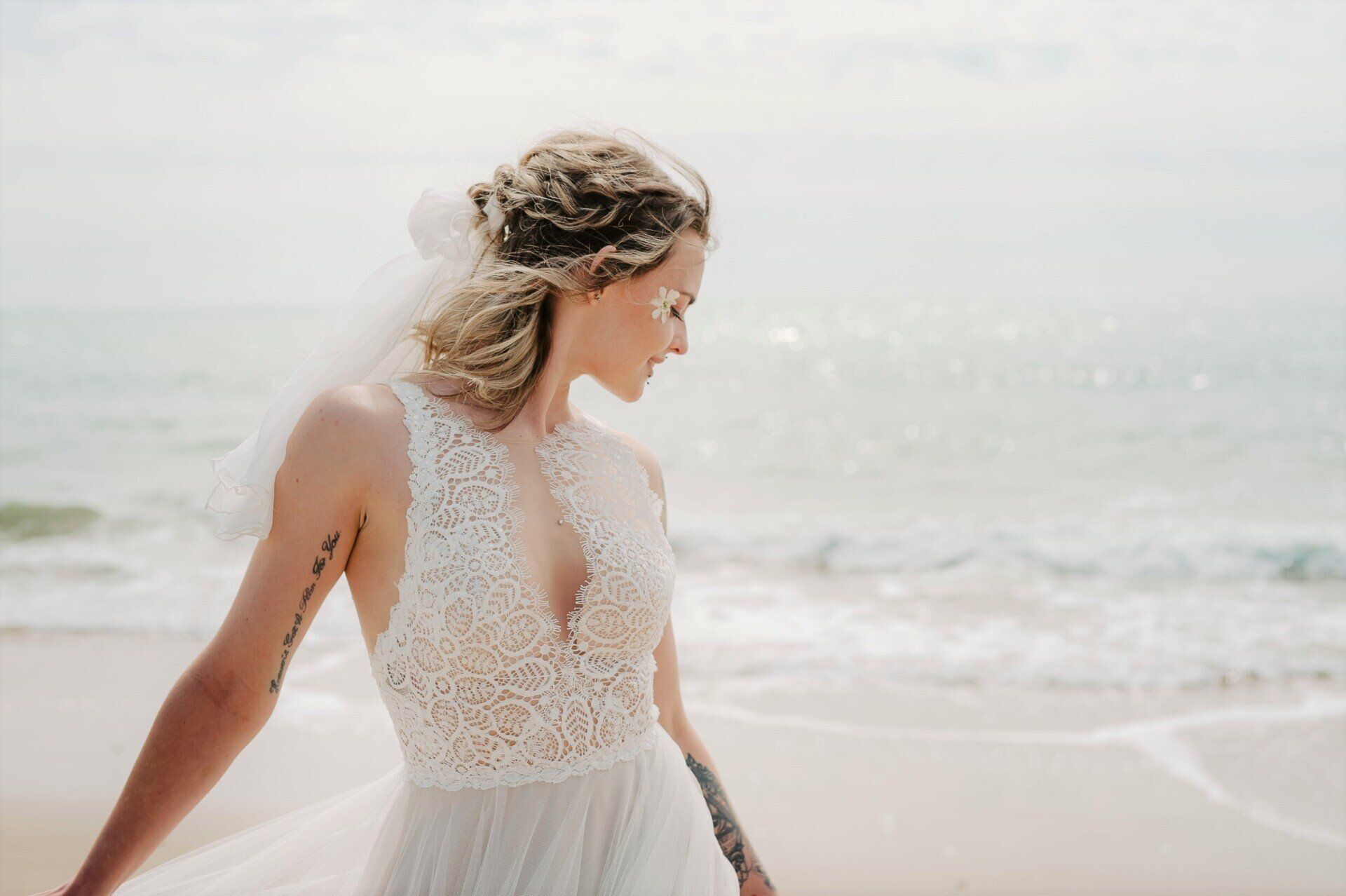 Bride looking down to sand on the shoreline at Highcliffe Beach in Dorset