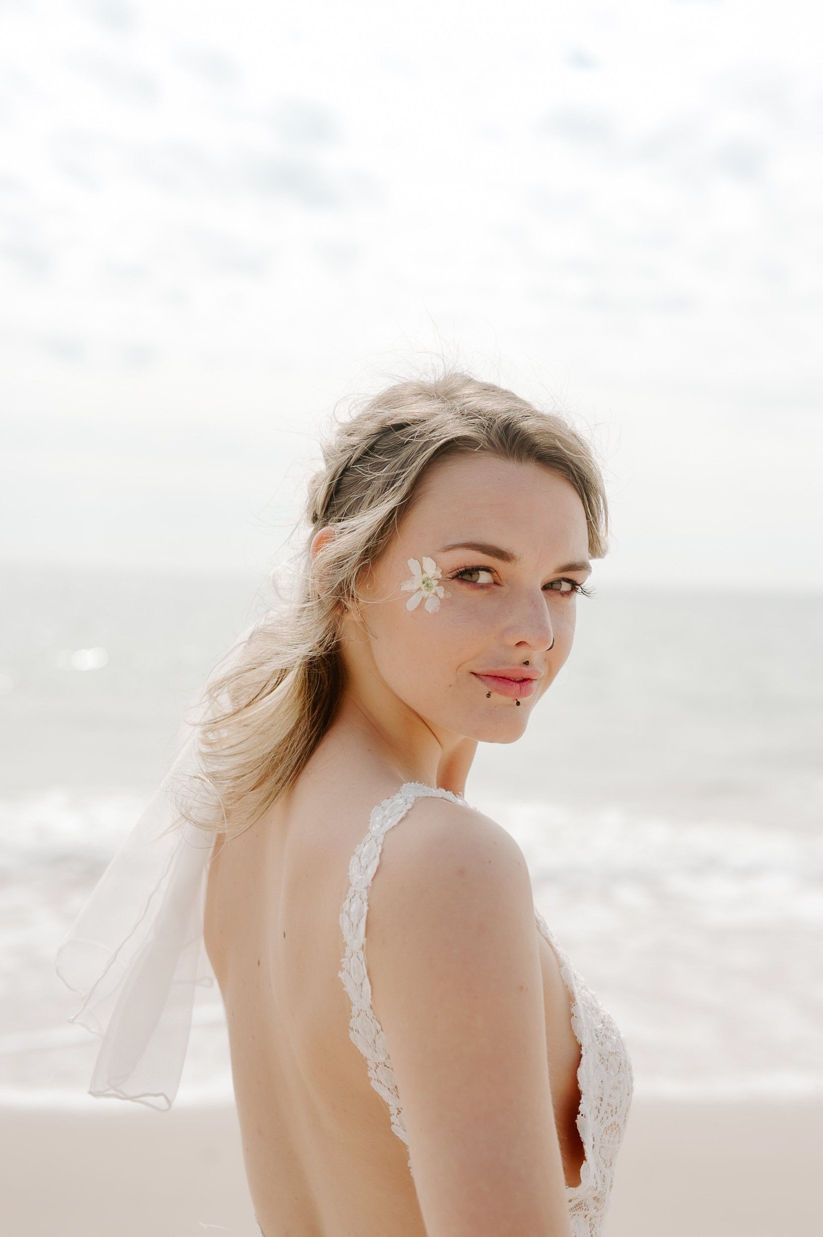 Bride on beach with dried flowers round her eyes and the sea in background