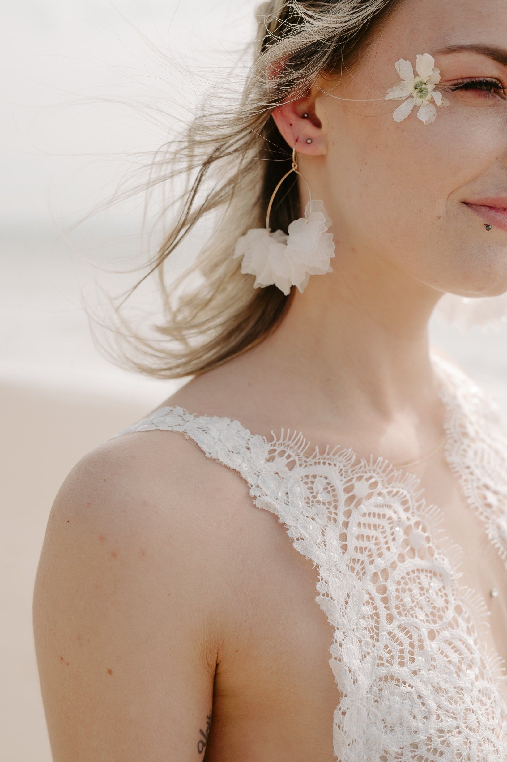 Side of brides head wearing a wedding dress and large clustered gold hoop earrings