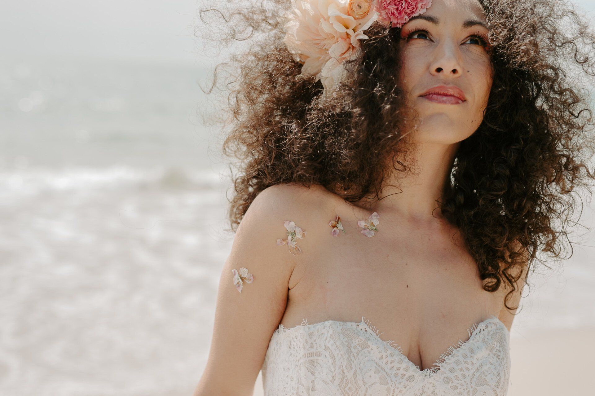 Close up of bride with afro hair and big flowers in it with dried flowers on her body