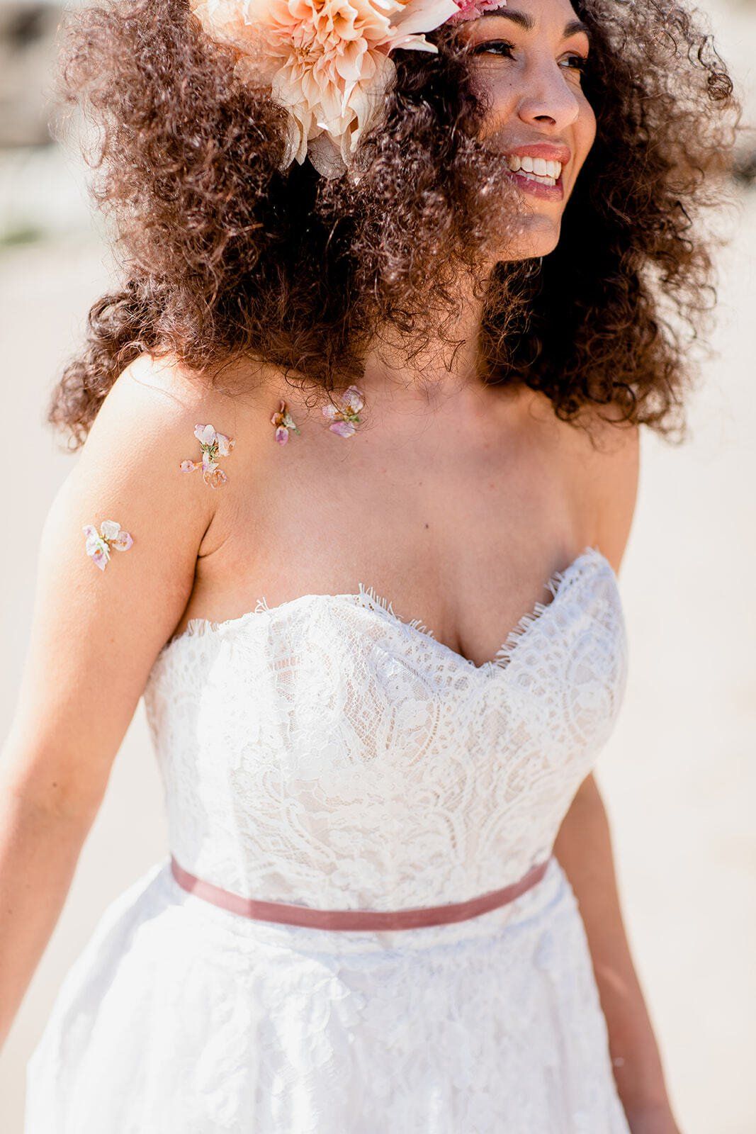 Bride with afro hair and big flowers in her hair wearing a wedding dress