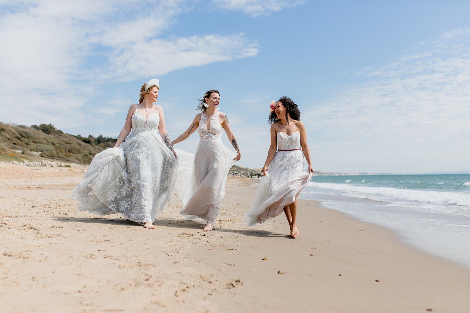 3 brides walking along the sand on Highcliffe Beach in Dorset