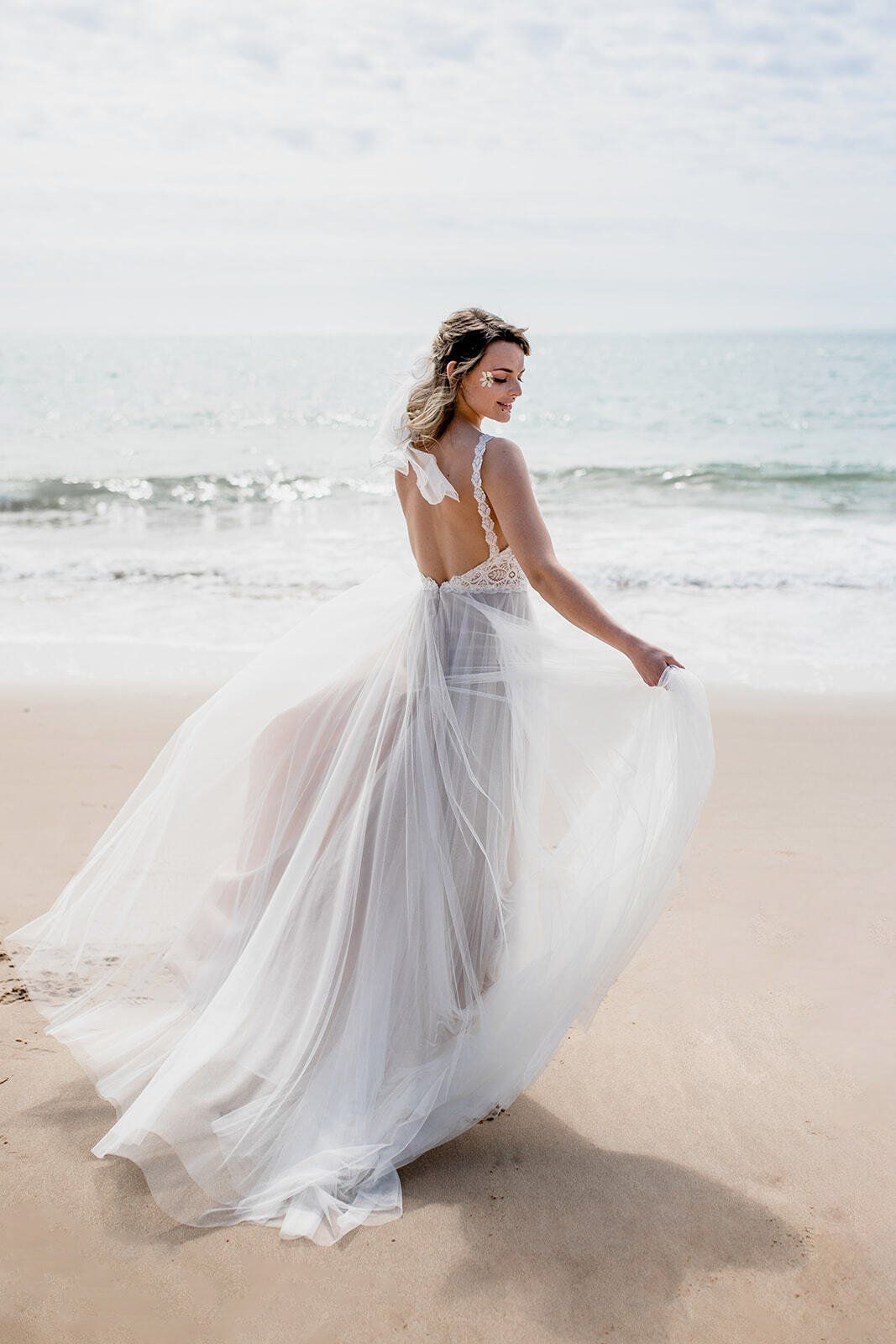 Bride fanning her wedding dress out on Highcliffe Beach in Dorset
