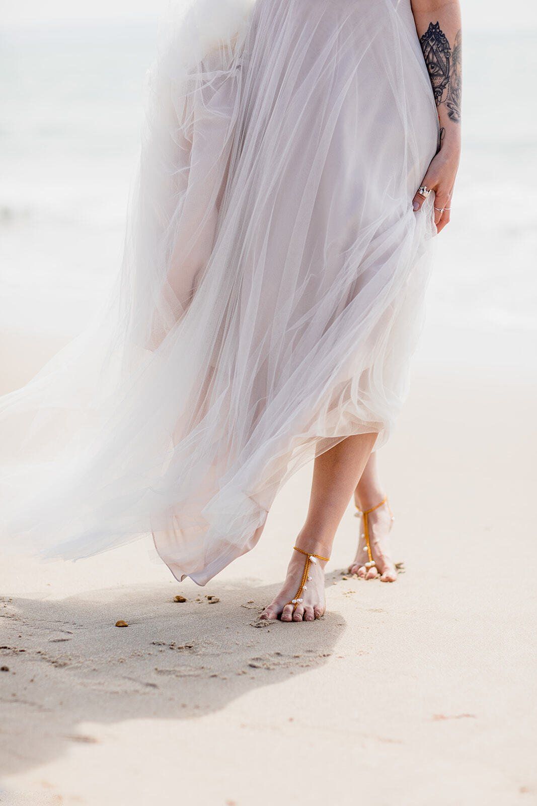 Close up of Brides feet wearing pearl barefoot sandals on the beach