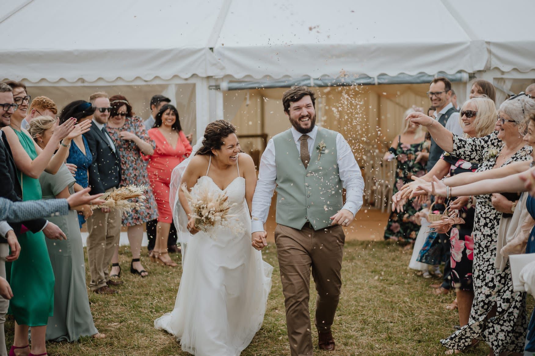 Bride and Groom walking through confetti outside a marquee co-ordinated by tasha -Mae Wedding Co-ordinator.
