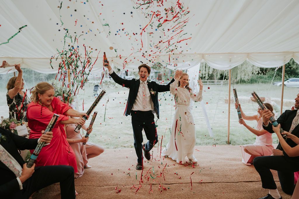 Bride and Groom walking through a confetti tunnel co-ordinated by Tasha Mae Wedding Co-ordinator