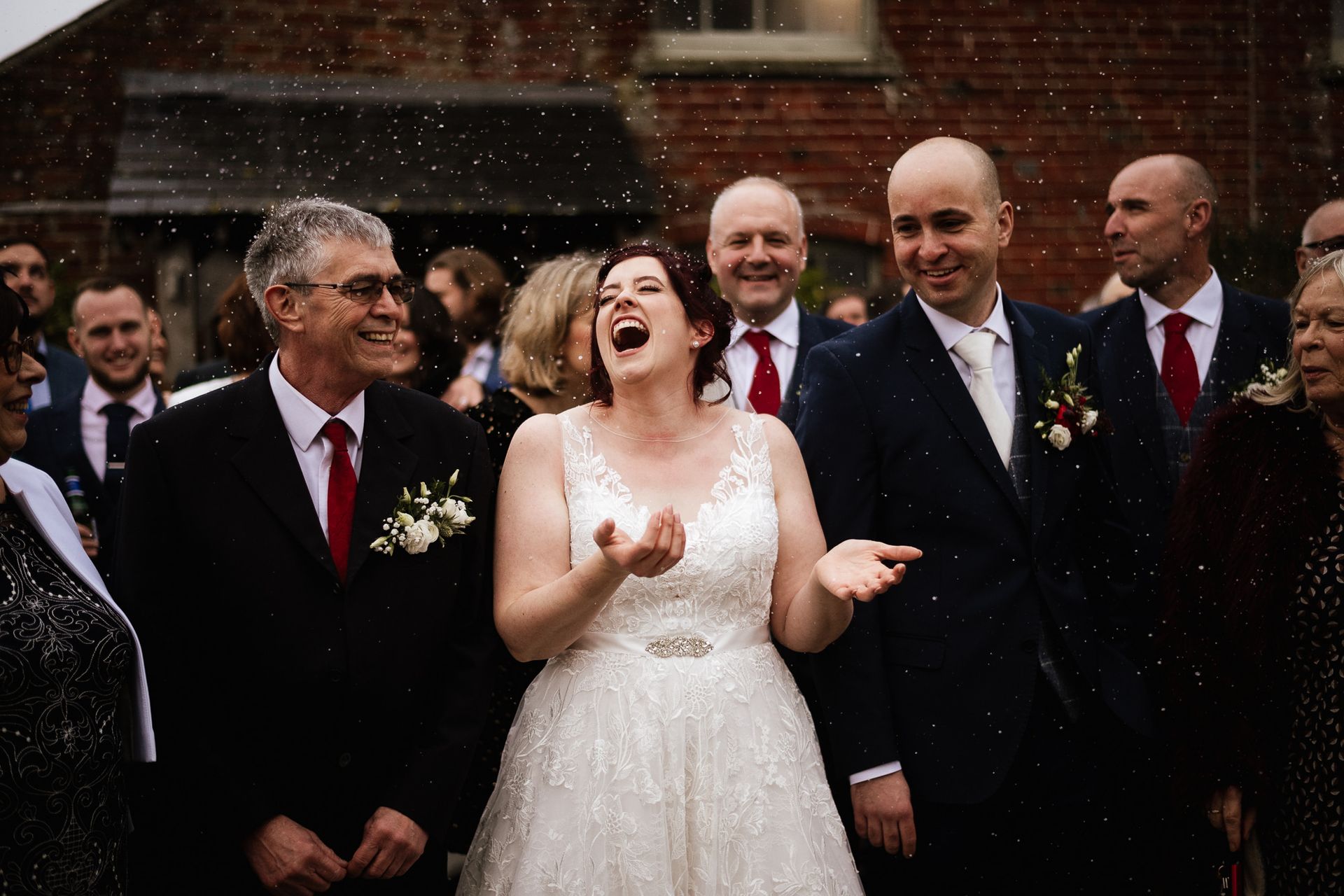 Bride and groom with family under a snow machine at a wedding at Sopley Mill with Tasha Mae Wedding Co-ordinator.