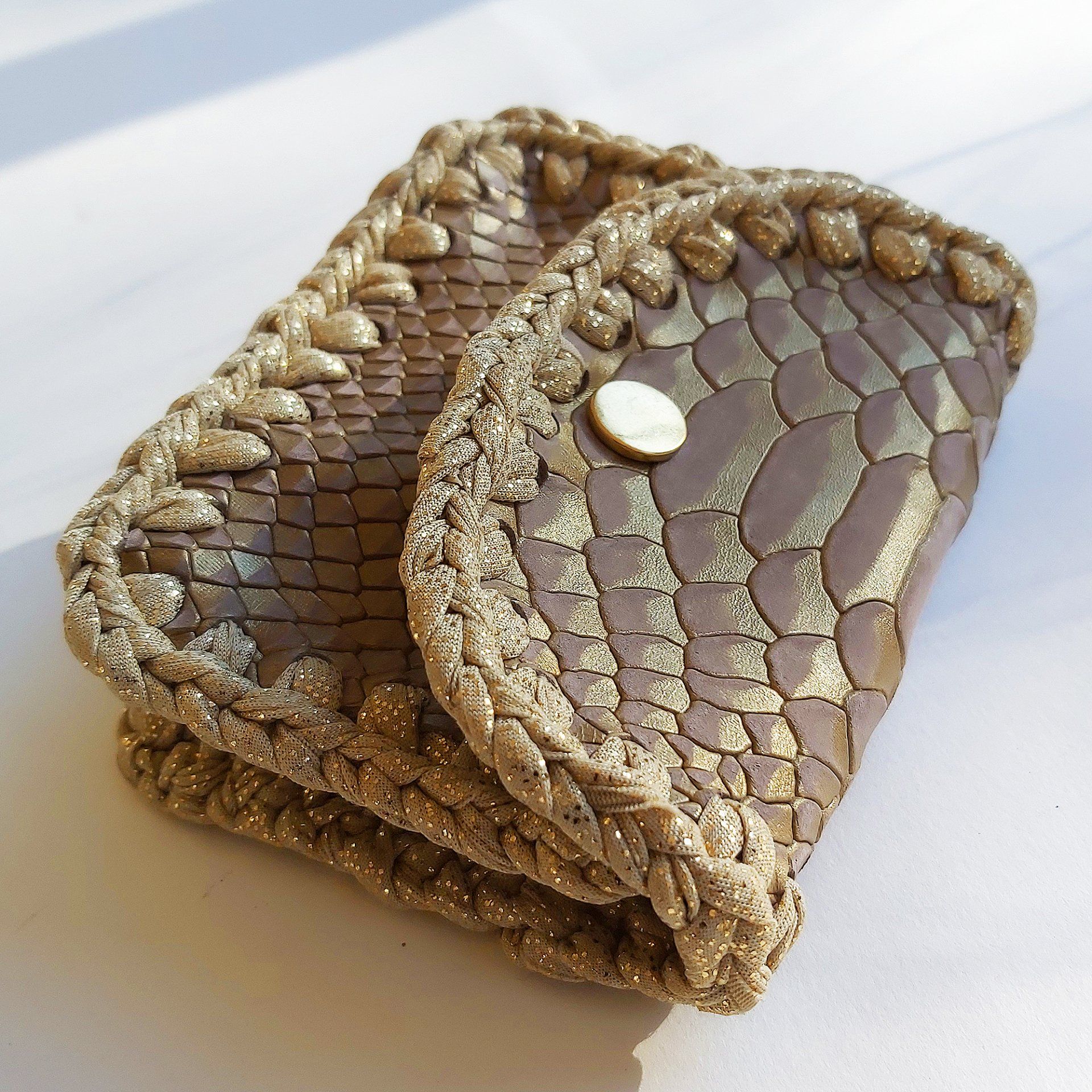 T-jolie, création fait main d'un porte-monnaie en cuir de veau relief serpent et crochet de tissu doré. Fermé avec un bouton pression couleur bronze.