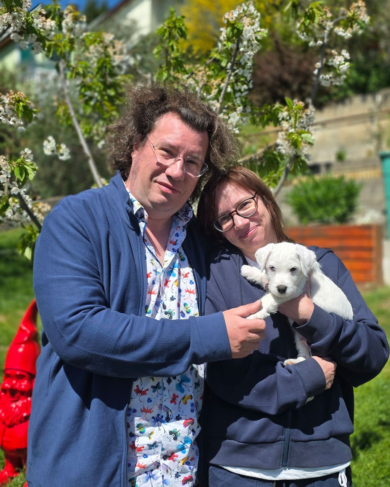 Eine Frau und ein Mann halten einen Parson Russell Terrier von of-Green-Spirits im Garten in den Händen