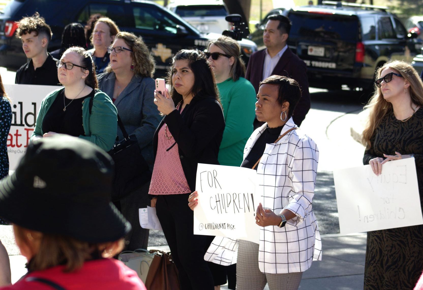 Demonstrators outside one holding a sign that says