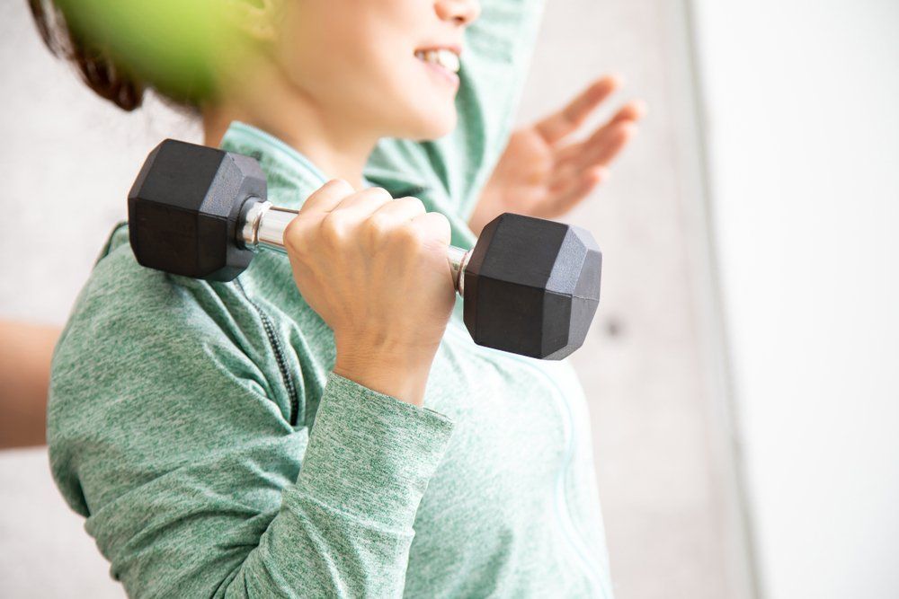 Frau mit Hantel in der rechten Hand