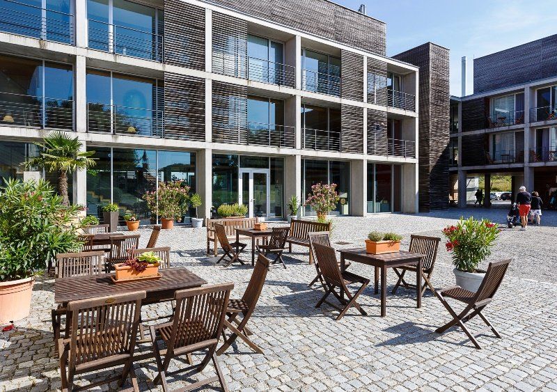 Tische und Stühle aus Holz vor dem Hotelgebäude des Fuerstlichen Golf-und Natur-Resorts Bad Waldsee