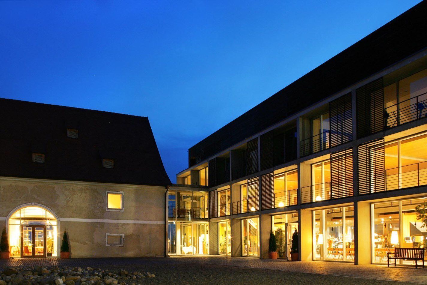 Liebevoll restauriertes Hofgut‑Gebäude und Hotel bei bei Nacht beleuchtet.
