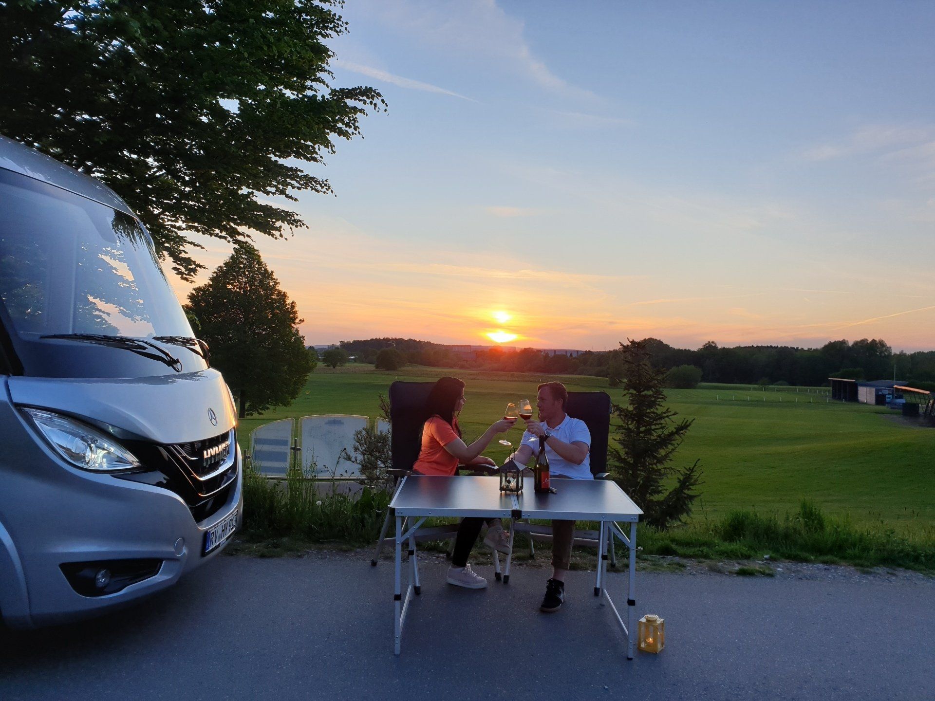 Wohnmobilplatz bei Sonnenuntergang mit beleuchtetem Golfplatz