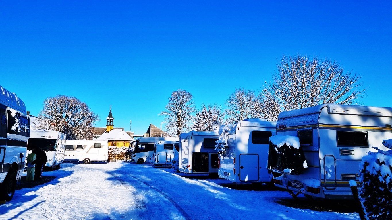 Wohnwagen und Wohnmobile auf Fuerstlichem Stellplat Bad Waldsee im Schnee bei Sonnenschein