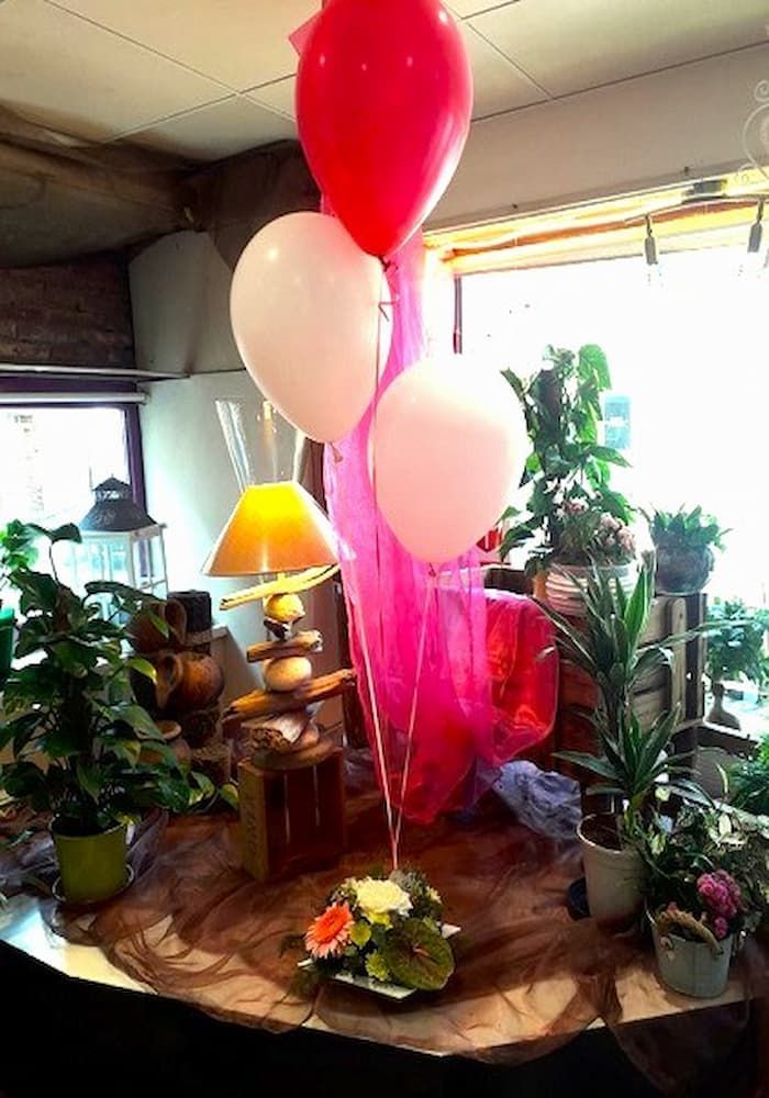 Décoration de mariage en Normandie : Bouquet de ballons hélium rouge et blanc avec arrangement floral à la base et tissu rose.