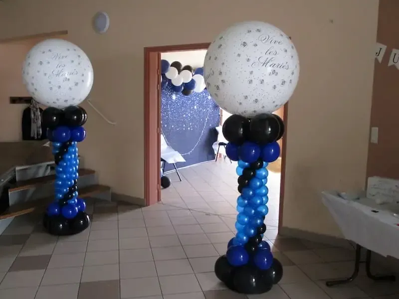 Colonnes totem ballons bleu et noir avec globes blancs Vive les Mariés encadrant l'entrée d'une salle de mariage en Normandie