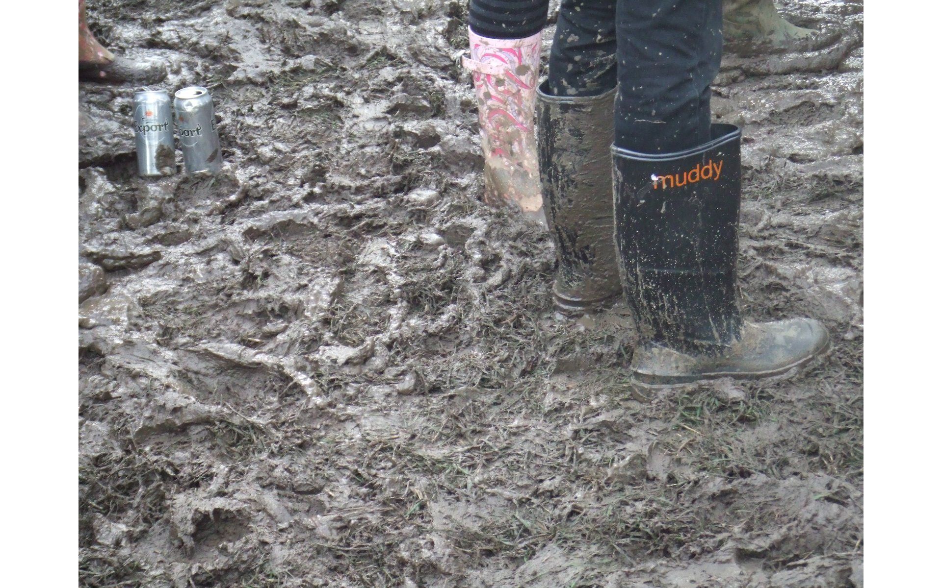 wellington boots in a muddy glastonbury festival field