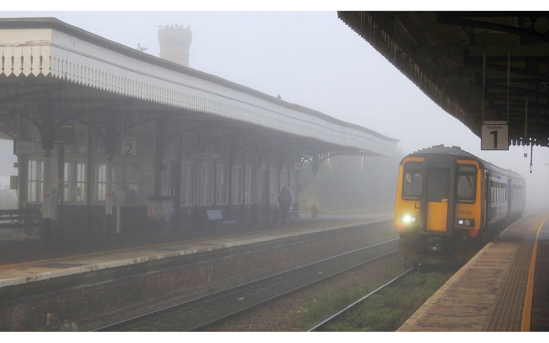 a passenger train at a station in fog
