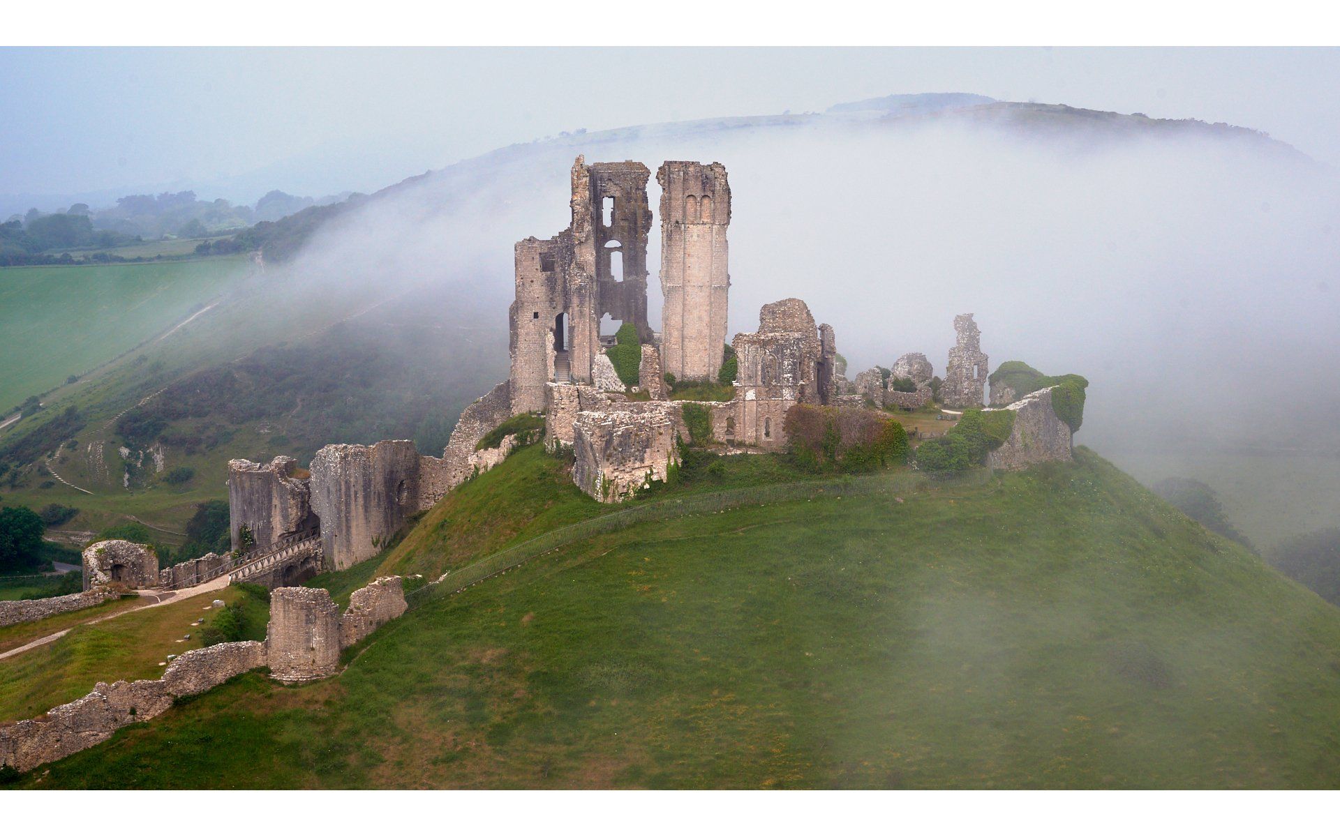 a view of corfe castle in the dawn mist