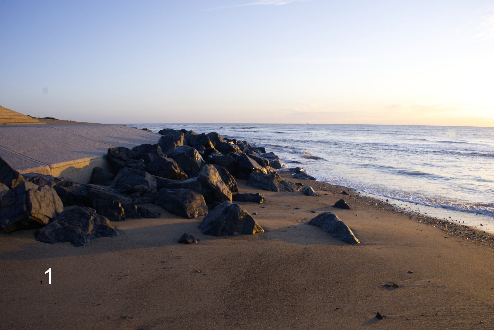 rocks on a lincolnshire beach lit by the sunrise