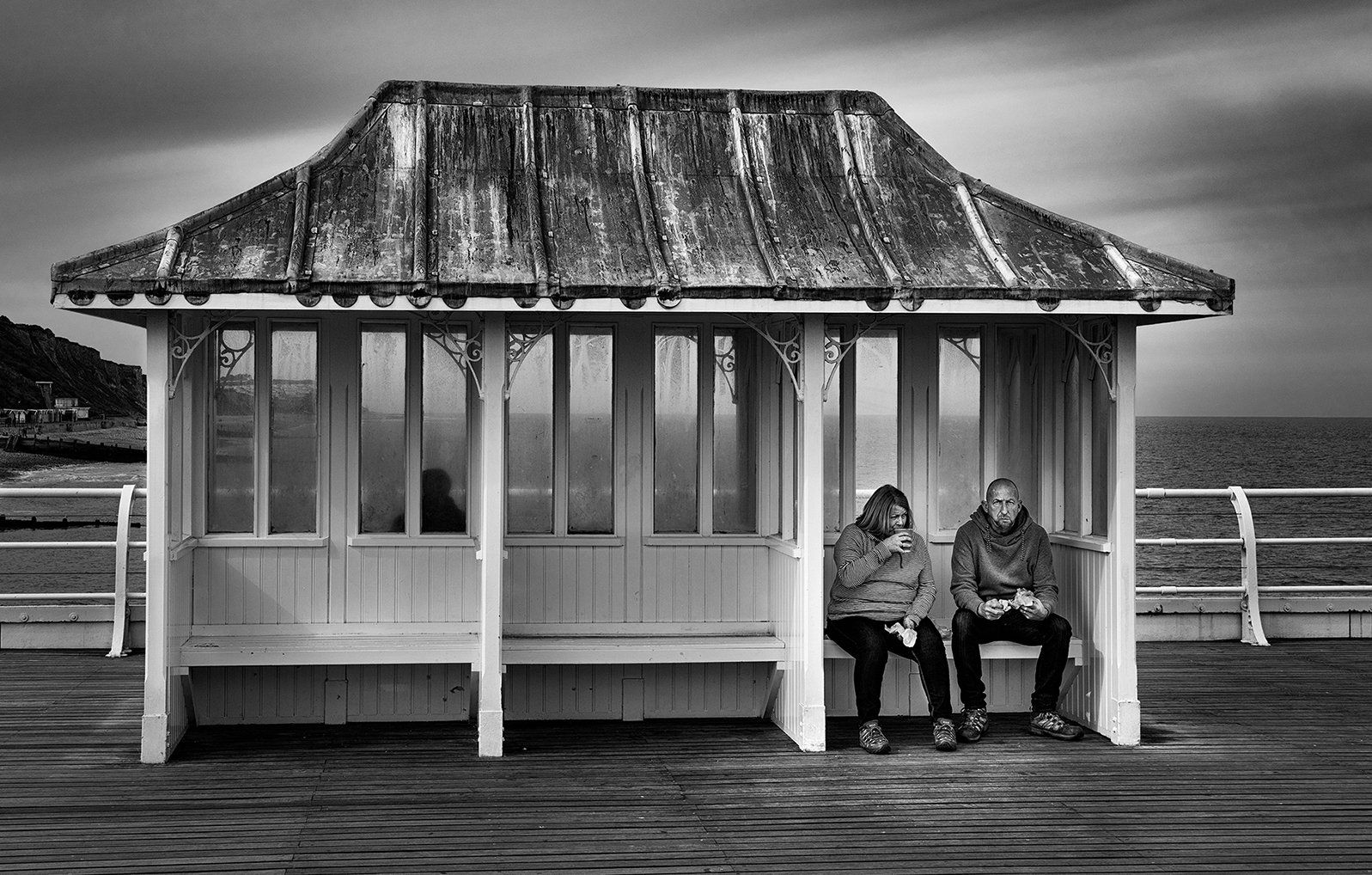 a monochrome view of a couple in a seaside shelter