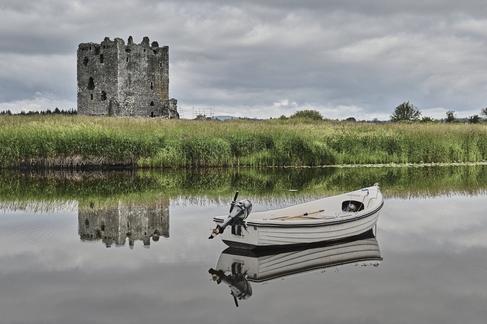 a moored boat on a river by a castle keep